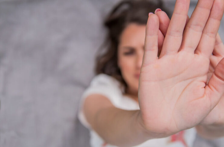 Young woman showing her denial with NO on her hand. Focus on hand. Timid woman symbol of violence in the family